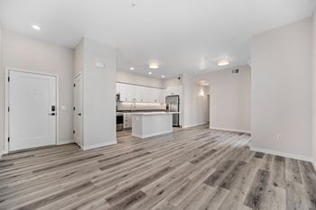 an empty living room and kitchen with white walls and wood flooring